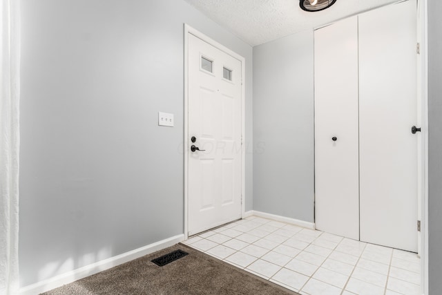 entryway with a textured ceiling and light tile patterned flooring