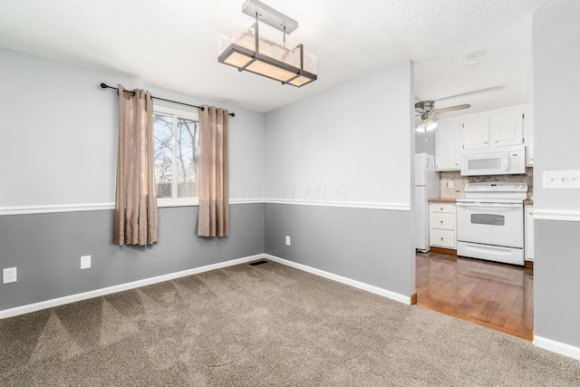 interior space featuring dark colored carpet, ceiling fan, and a textured ceiling