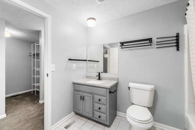 bathroom with tile patterned floors, vanity, toilet, and a textured ceiling