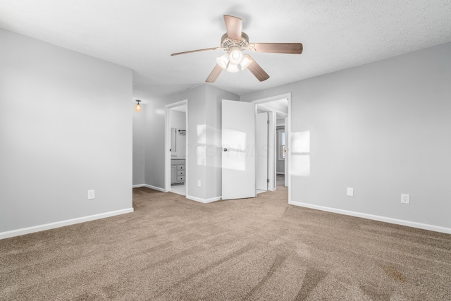 unfurnished bedroom featuring a textured ceiling, connected bathroom, carpet floors, and ceiling fan