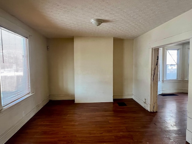 spare room with dark wood-type flooring and a textured ceiling