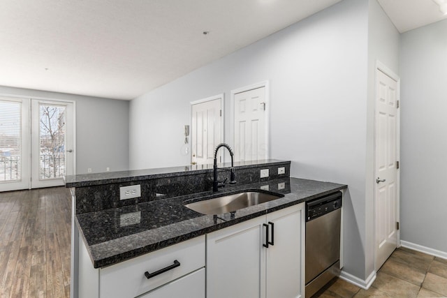 kitchen featuring dark stone countertops, sink, white cabinets, and stainless steel dishwasher