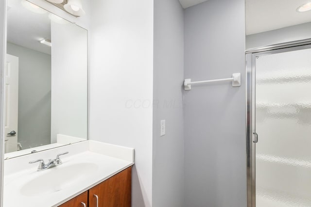 bathroom featuring vanity and a shower with door