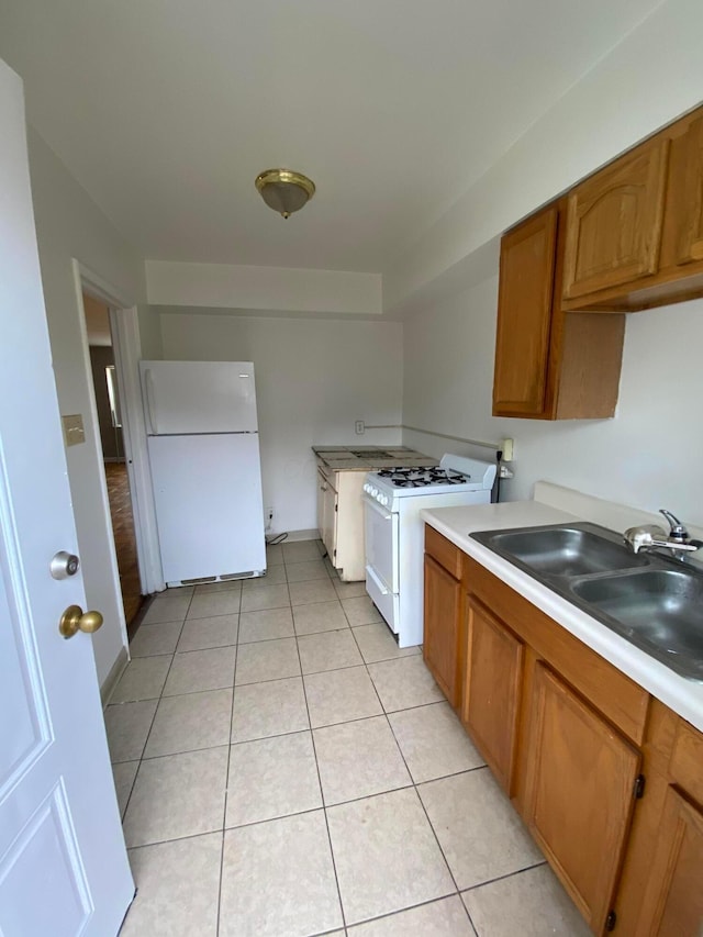 kitchen with light tile patterned floors, white appliances, and sink