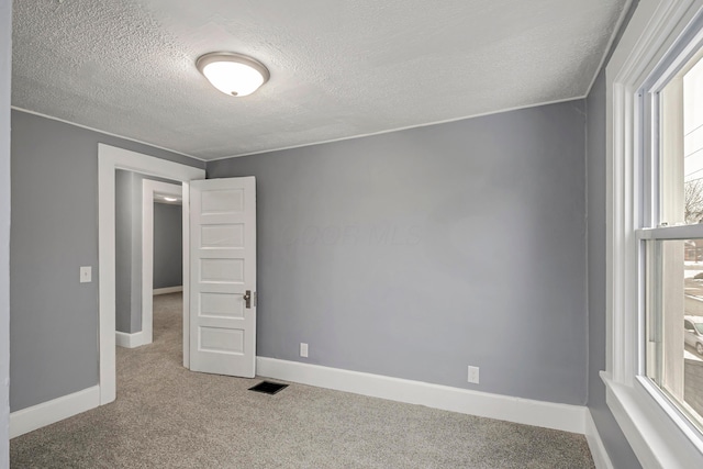 unfurnished room featuring carpet and a textured ceiling