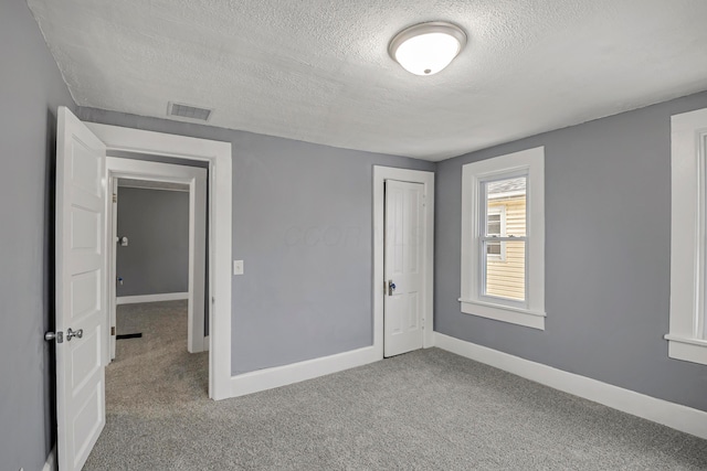 carpeted spare room with a textured ceiling