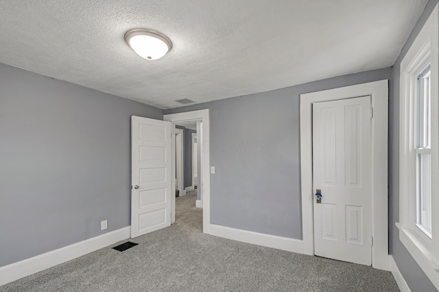 unfurnished bedroom with a textured ceiling, light carpet, and a closet