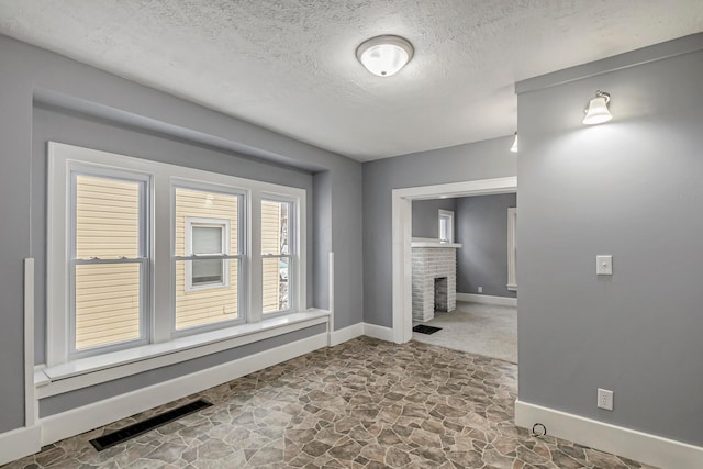 interior space with a textured ceiling and a brick fireplace