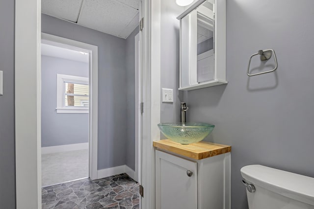 bathroom featuring a paneled ceiling, vanity, and toilet