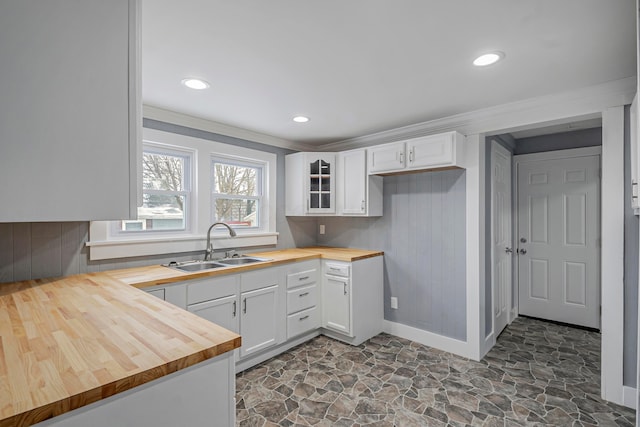 kitchen featuring wood counters, white cabinets, ornamental molding, and sink