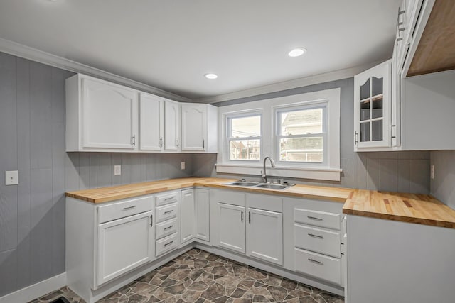 kitchen with white cabinets, wood counters, ornamental molding, and sink