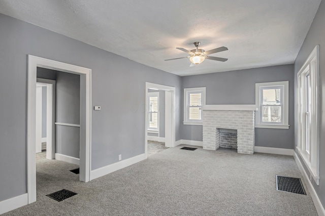 carpeted living room with a fireplace, a textured ceiling, ceiling fan, and a healthy amount of sunlight