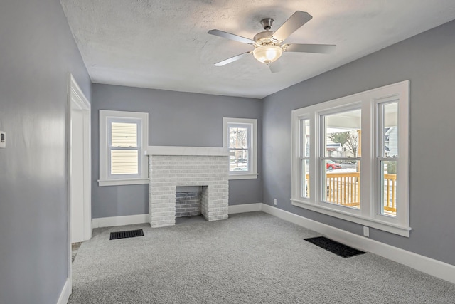 unfurnished living room featuring light carpet, a brick fireplace, ceiling fan, and plenty of natural light