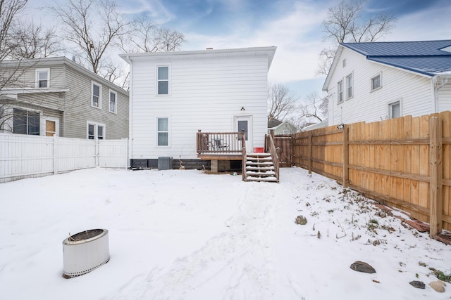 snow covered house with a wooden deck and cooling unit