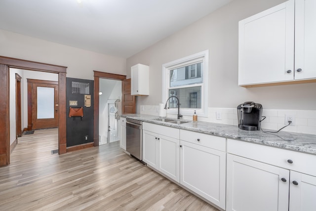 kitchen with light stone countertops, dishwasher, white cabinets, and sink