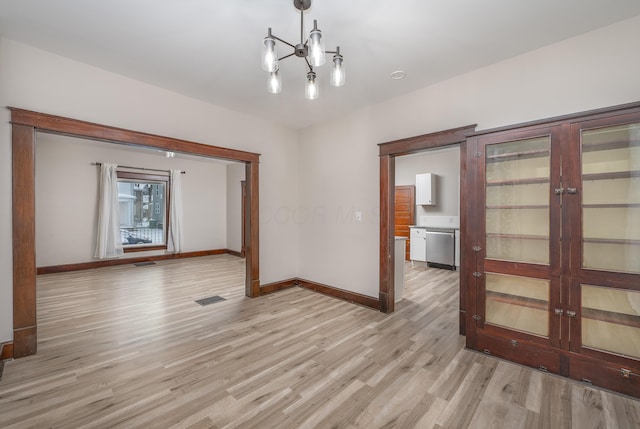 spare room with french doors, light hardwood / wood-style flooring, and a notable chandelier