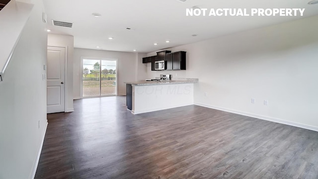 kitchen featuring kitchen peninsula, light stone countertops, stainless steel appliances, and dark hardwood / wood-style floors