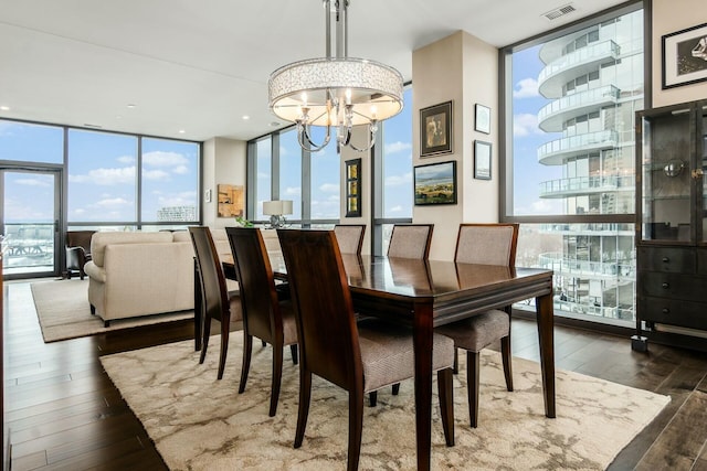 dining area with a wall of windows, dark wood-type flooring, and an inviting chandelier