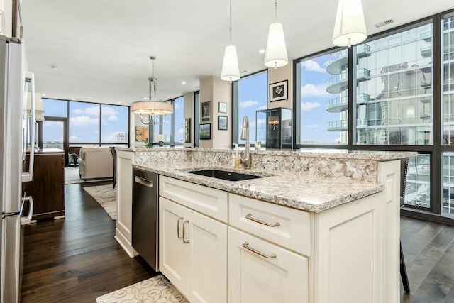 kitchen featuring dark hardwood / wood-style flooring, light stone counters, sink, pendant lighting, and white cabinetry