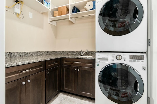 washroom with stacked washer / dryer, sink, light tile patterned flooring, and cabinets