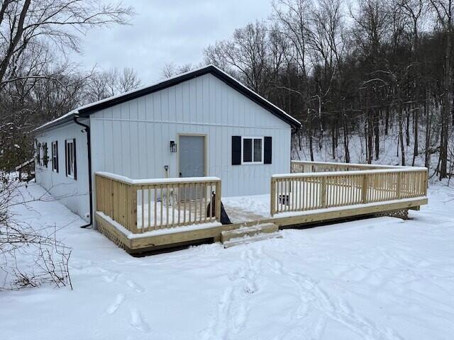 snow covered rear of property featuring a wooden deck