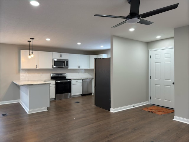 kitchen featuring appliances with stainless steel finishes, white cabinetry, decorative backsplash, decorative light fixtures, and dark wood-type flooring