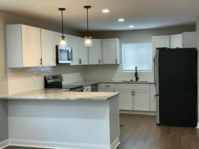 kitchen featuring white cabinetry, stainless steel appliances, decorative backsplash, sink, and kitchen peninsula