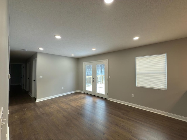 unfurnished room with a textured ceiling, dark hardwood / wood-style floors, and french doors