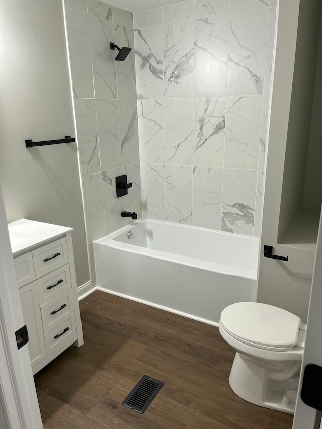 full bathroom with hardwood / wood-style flooring, toilet, tiled shower / bath, and vanity