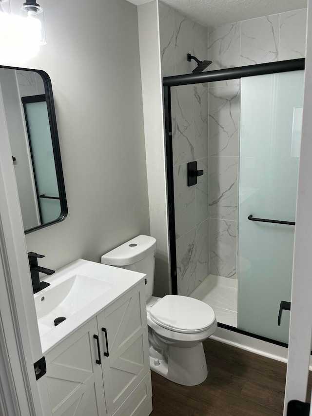 bathroom with toilet, a shower with door, hardwood / wood-style flooring, and vanity