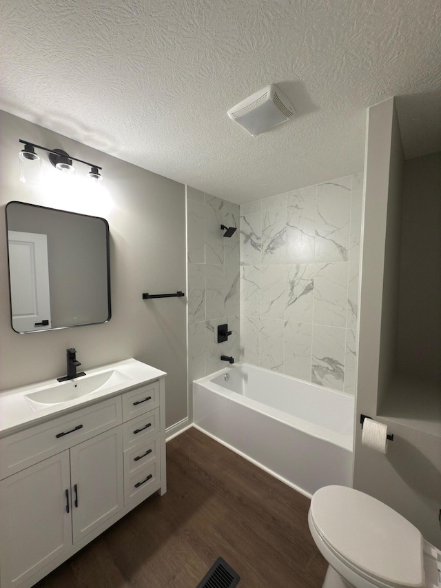 full bathroom featuring toilet, a textured ceiling, hardwood / wood-style flooring, vanity, and tiled shower / bath