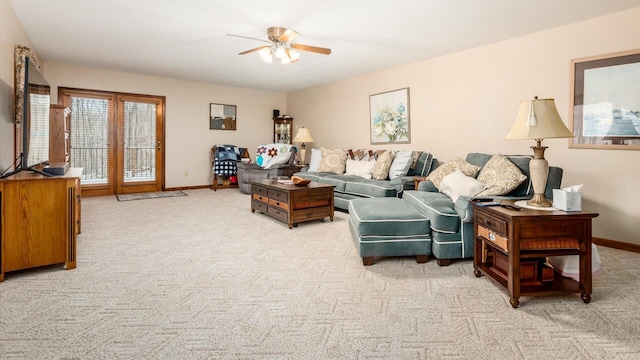 living area featuring light carpet, ceiling fan, and baseboards