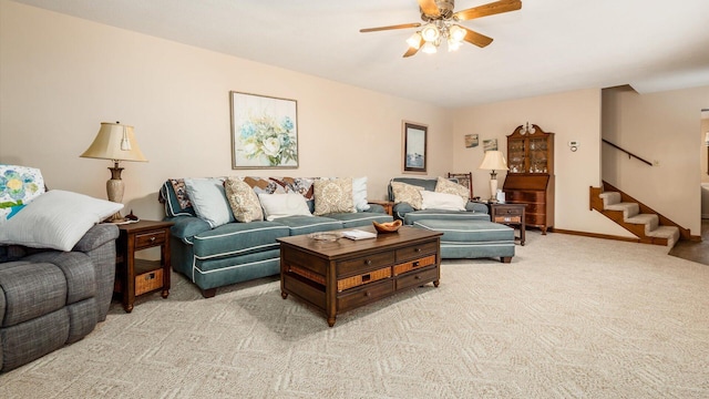 living room with carpet floors, ceiling fan, baseboards, and stairs