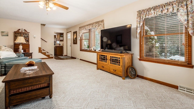 carpeted living area featuring visible vents, ceiling fan, stairway, and baseboards