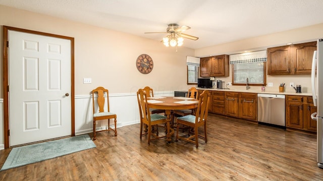 dining space with ceiling fan, dark wood-style flooring, and wainscoting