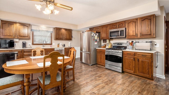 kitchen with brown cabinetry, appliances with stainless steel finishes, light countertops, and wood finished floors