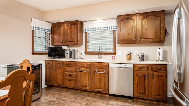 kitchen featuring wood finished floors, appliances with stainless steel finishes, a sink, and brown cabinets