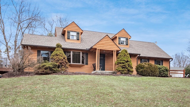 view of front facade featuring a shingled roof and a front yard