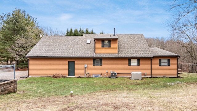 rear view of property with roof with shingles, a lawn, cooling unit, and fence