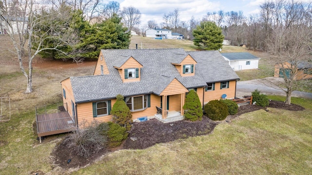 view of front of home with a front yard, roof with shingles, and a deck