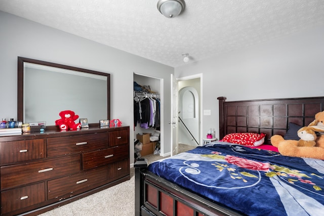 carpeted bedroom featuring a textured ceiling and a closet