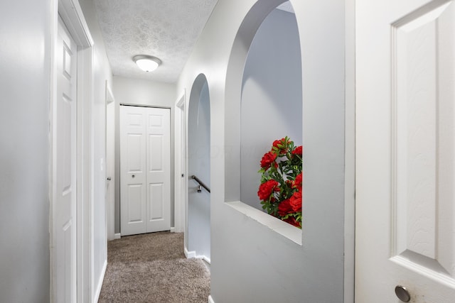 corridor with carpet and a textured ceiling