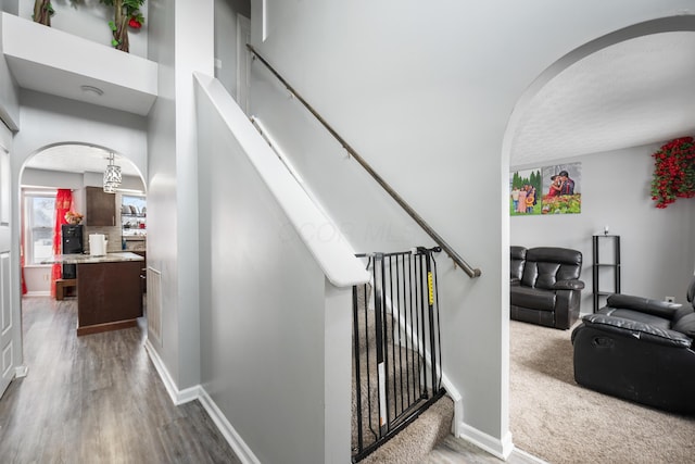 staircase with hardwood / wood-style floors and a towering ceiling