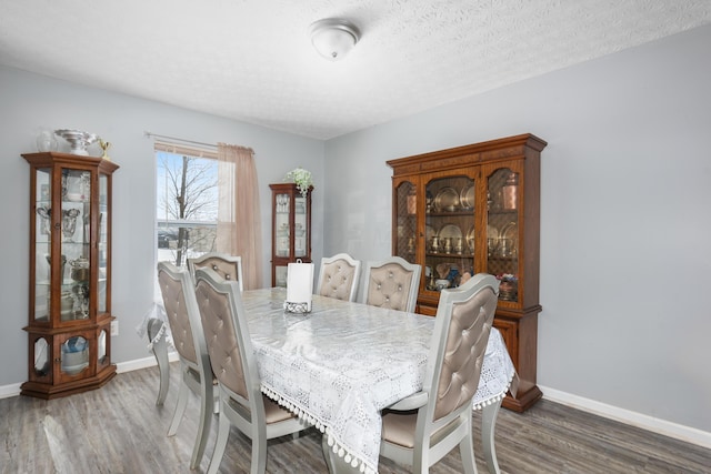 dining area featuring dark wood-type flooring and a textured ceiling