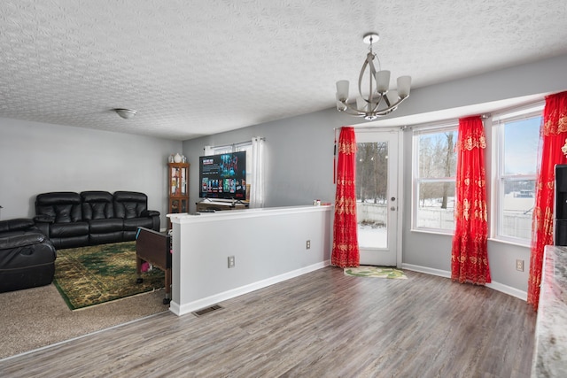 interior space featuring a healthy amount of sunlight, dark hardwood / wood-style flooring, a textured ceiling, and an inviting chandelier