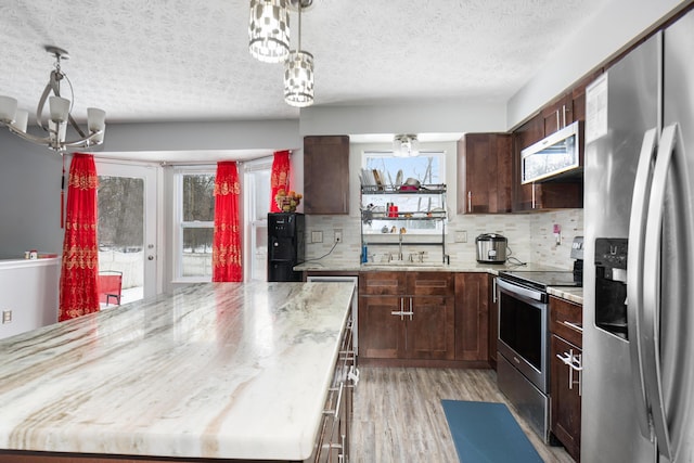 kitchen featuring tasteful backsplash, stainless steel appliances, sink, pendant lighting, and a chandelier