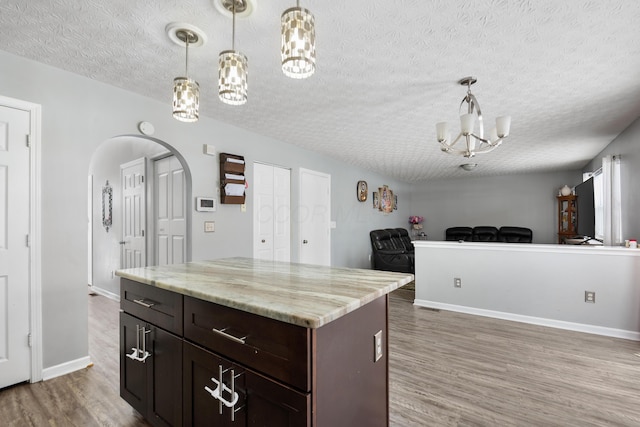 kitchen featuring dark brown cabinets, a chandelier, hardwood / wood-style floors, a center island, and hanging light fixtures