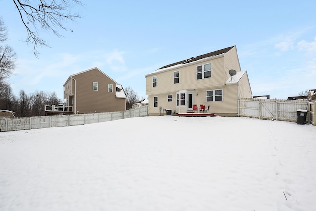 snow covered back of property with central air condition unit and a wooden deck