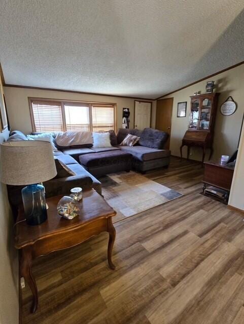 living room with lofted ceiling, crown molding, a textured ceiling, and wood finished floors