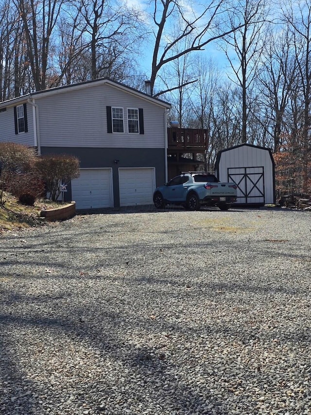 view of side of home featuring an outbuilding, a deck, an attached garage, driveway, and a storage unit